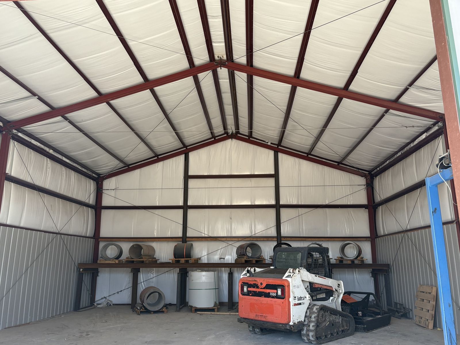 Insulated steel building with a skid steer and metal coils stored inside