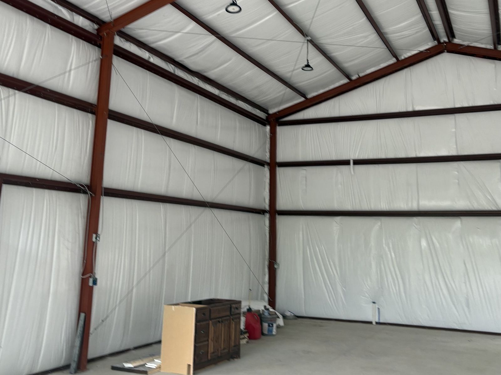 Finished steel building interior with white insulation, lights and a concrete floor