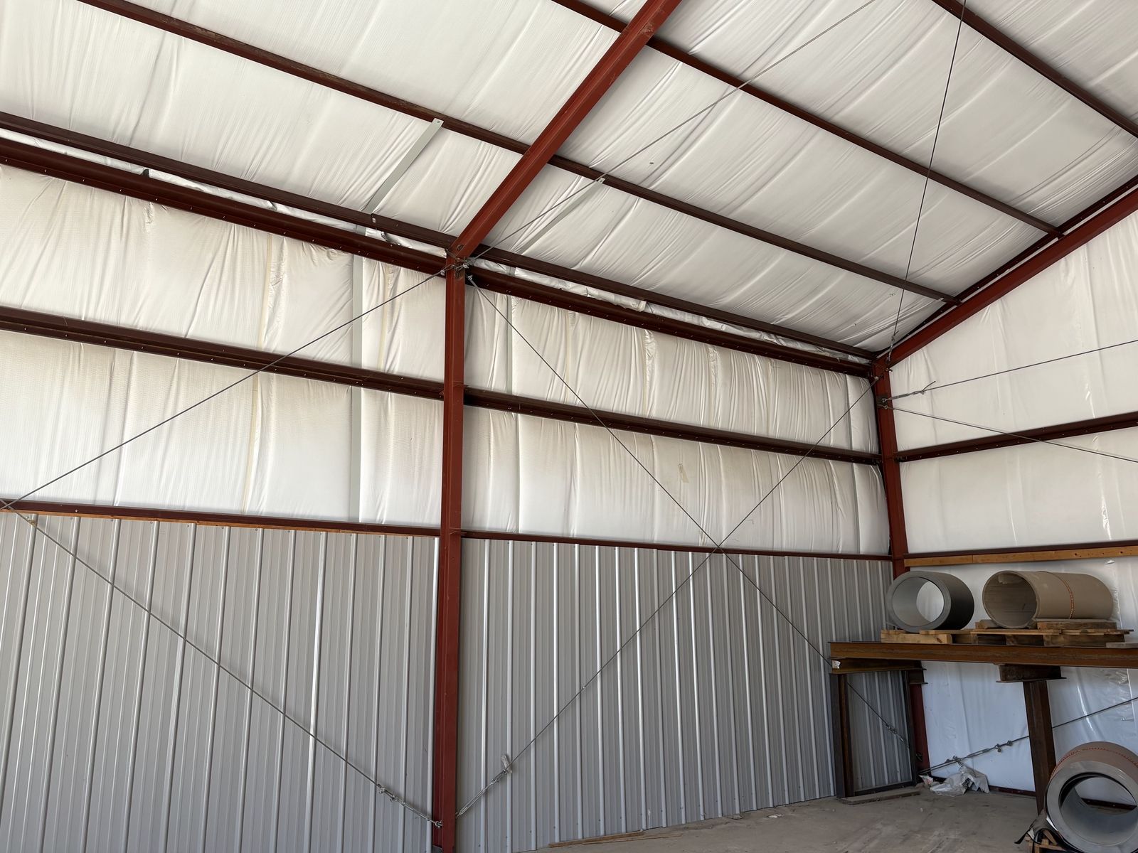 Insulated steel building interior with red framing and metal wainscot panels