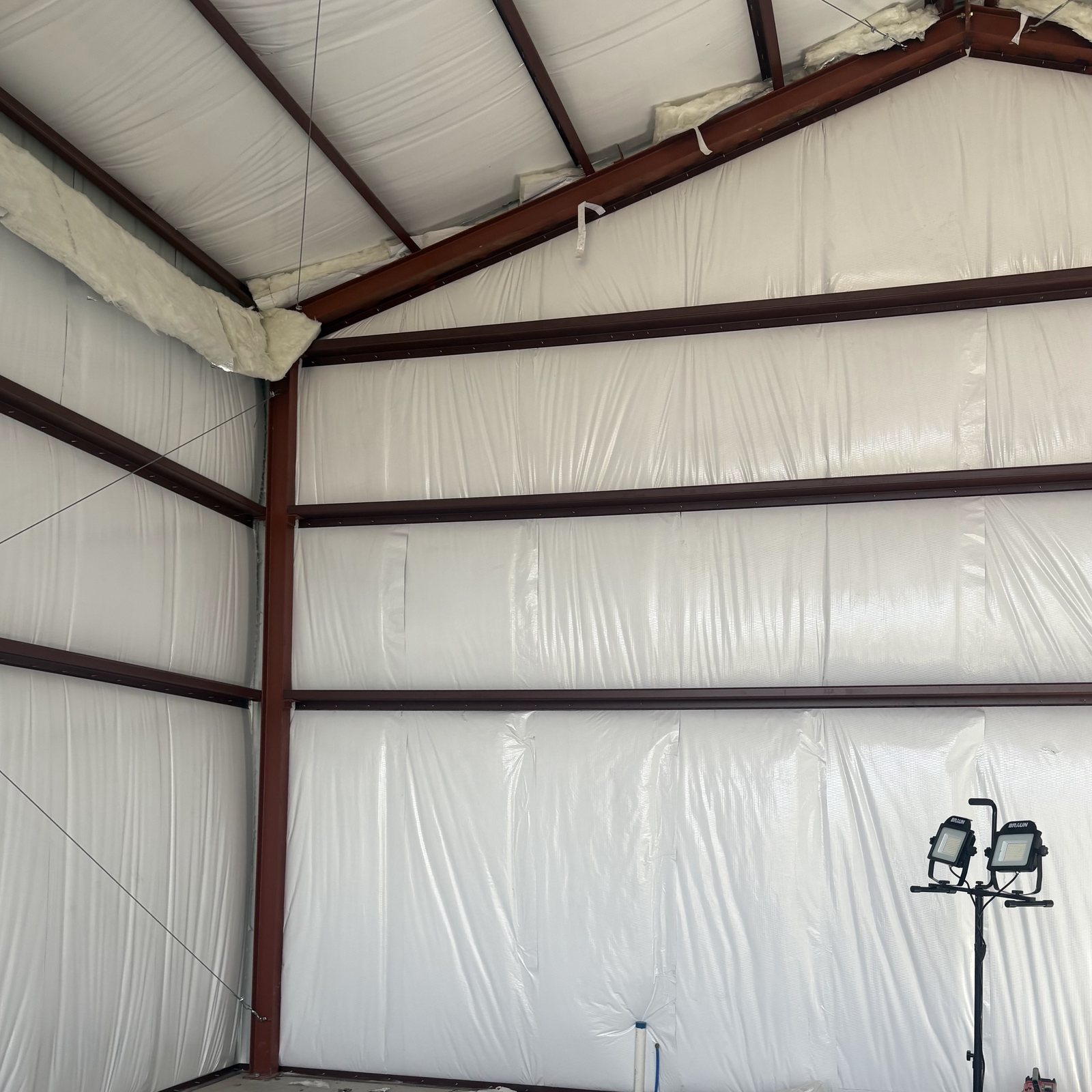Red steel rafters and purlins under white insulated roof panels