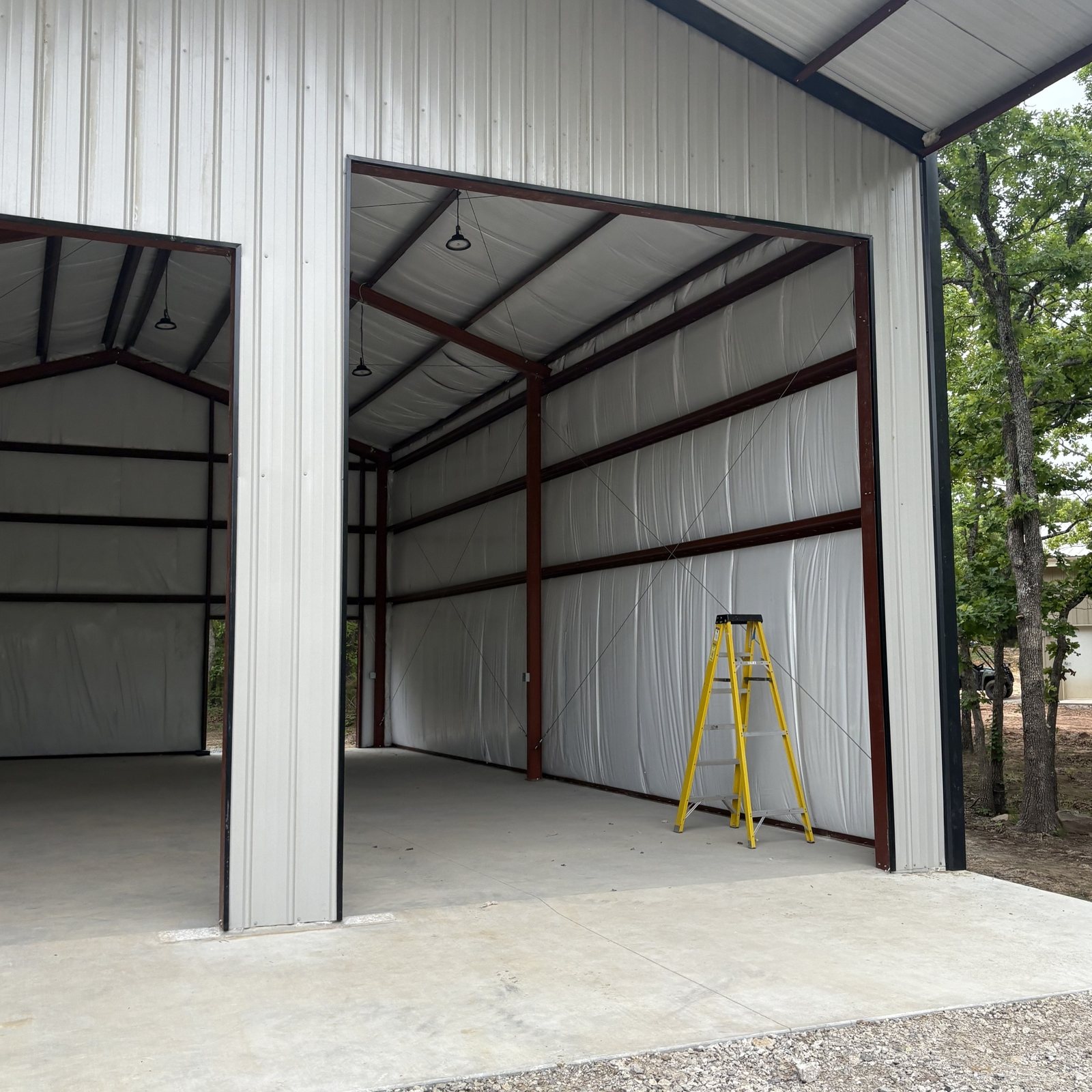 Finished white steel building with wide open doors, an insulated interior and a new concrete slab
